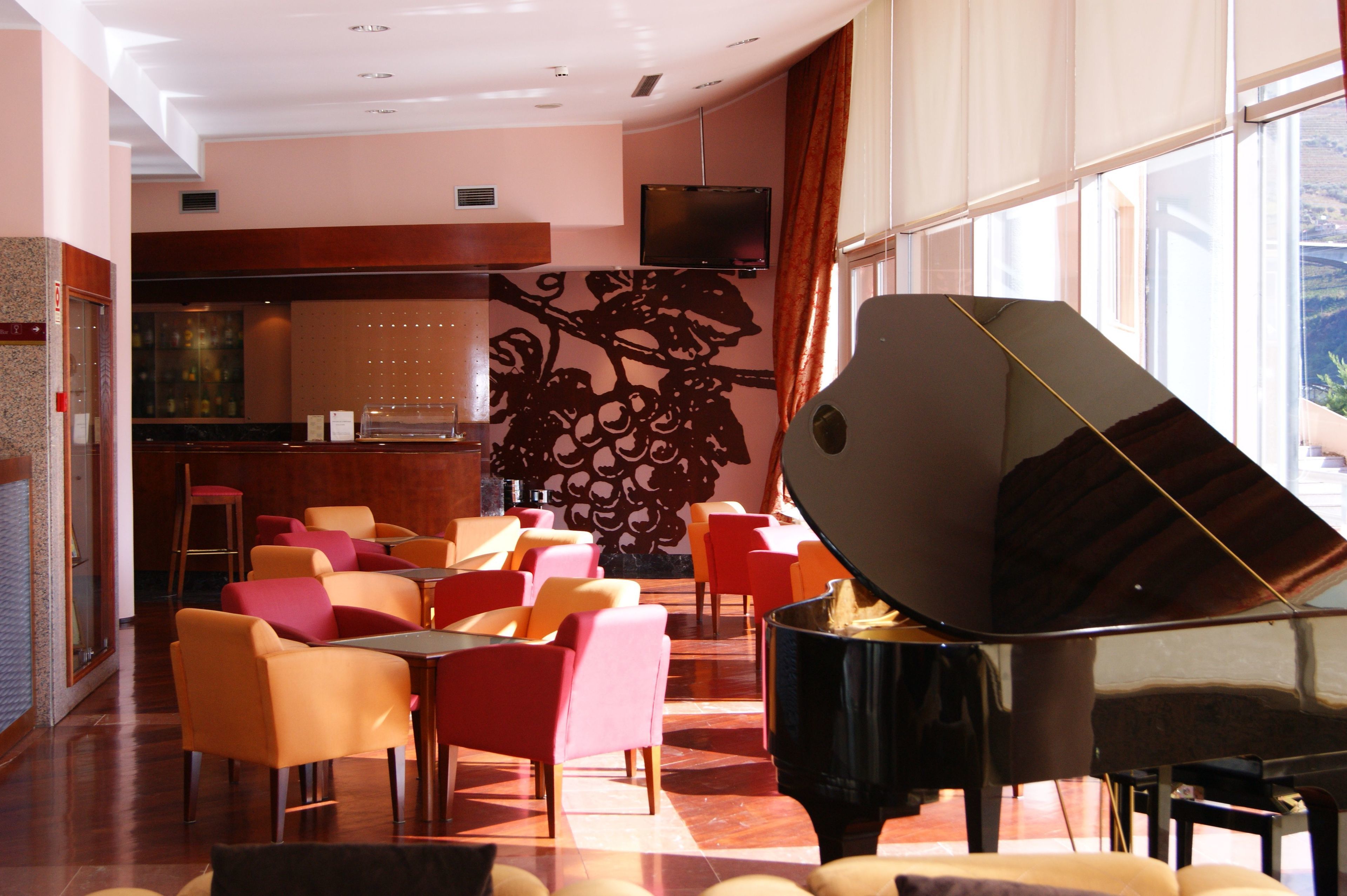 A hotel lobby with a grand piano, multiple seating areas, a bar, and large windows.