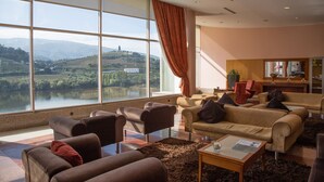 A modern living room with large windows, a sofa set, and a view of a lake and hills.
