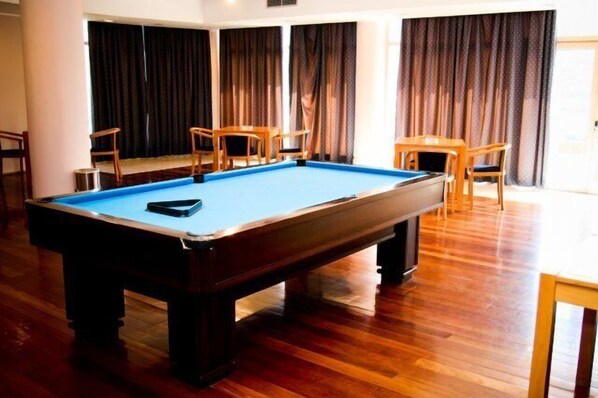 A pool table in a room with wooden flooring, curtains, and wooden furniture. - Crisol Régua Douro (Peso da Régua)