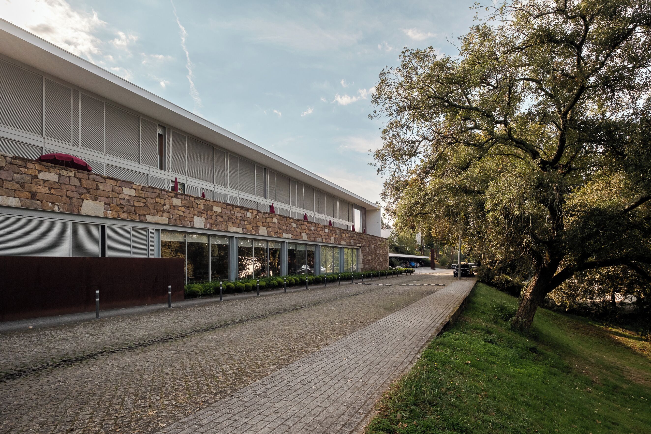 A modern building with a brick facade, large windows, and a paved walkway.