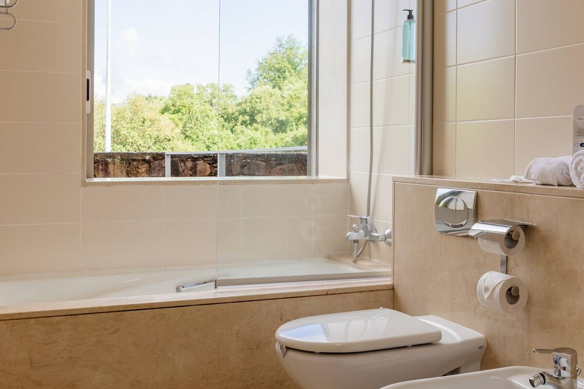 Een moderne badkamer met een bad, toilet en bidet.