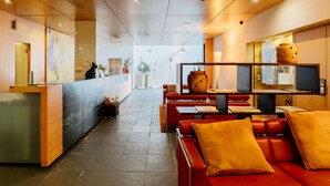 A modern hotel lobby with a reception desk, seating area, and a large window. - Axis Ponte de Lima Golf Resort Hotel (Ponte de Lima)
