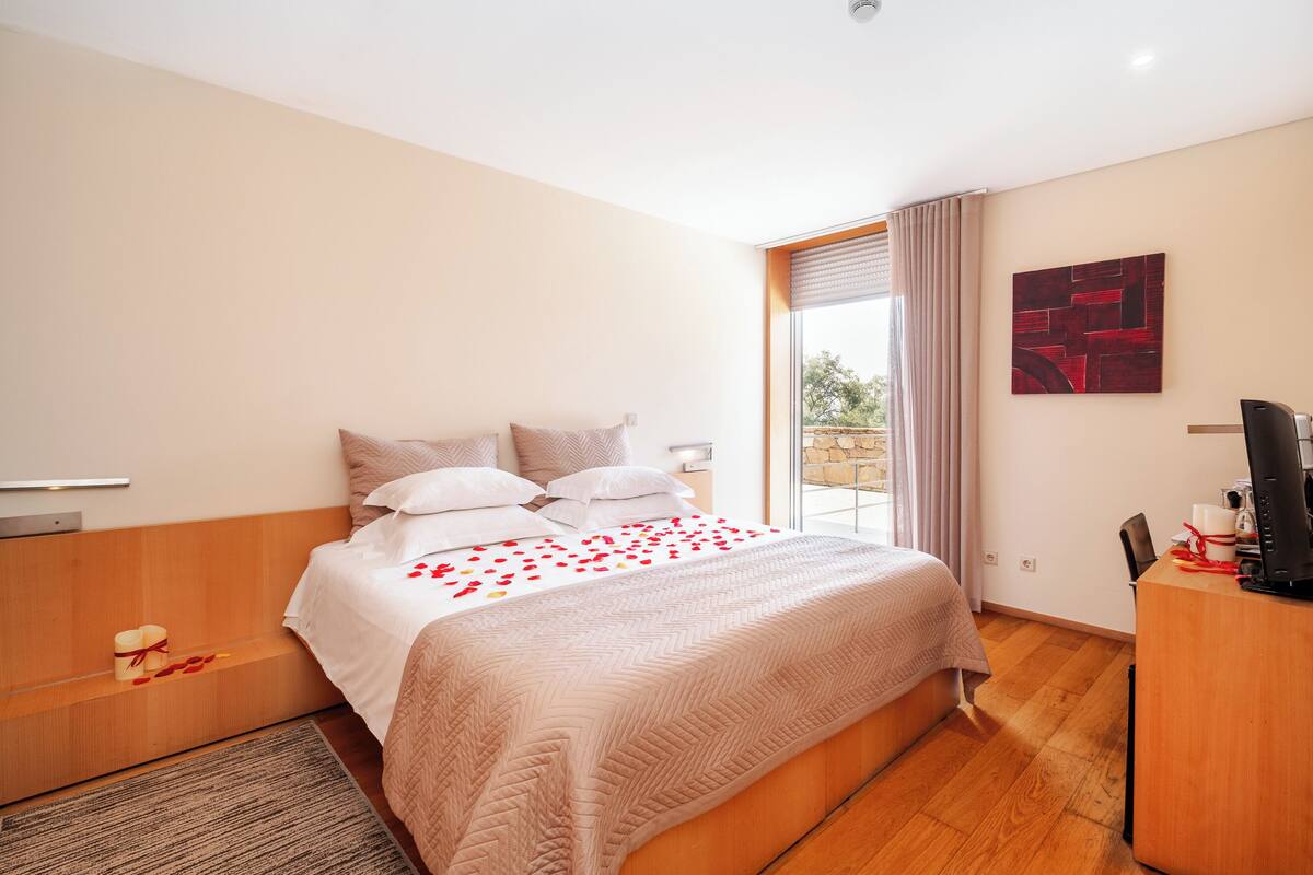 Een moderne hotelkamer met een groot bed, een bureau en een raam met gordijnen.