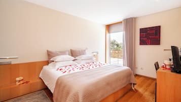 A modern hotel room with a large bed, a desk, and a window with curtains.