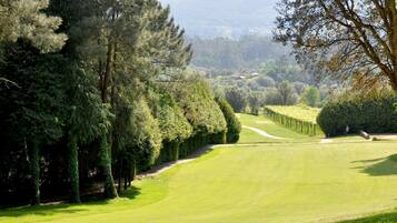 Un campo de golf bien cuidado con setos y árboles ordenados a lo largo del fairway.
