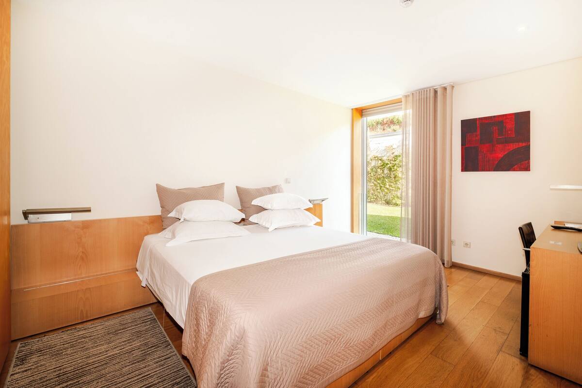Een hotelkamer met een groot bed, een bureau en uitzicht op de omgeving.