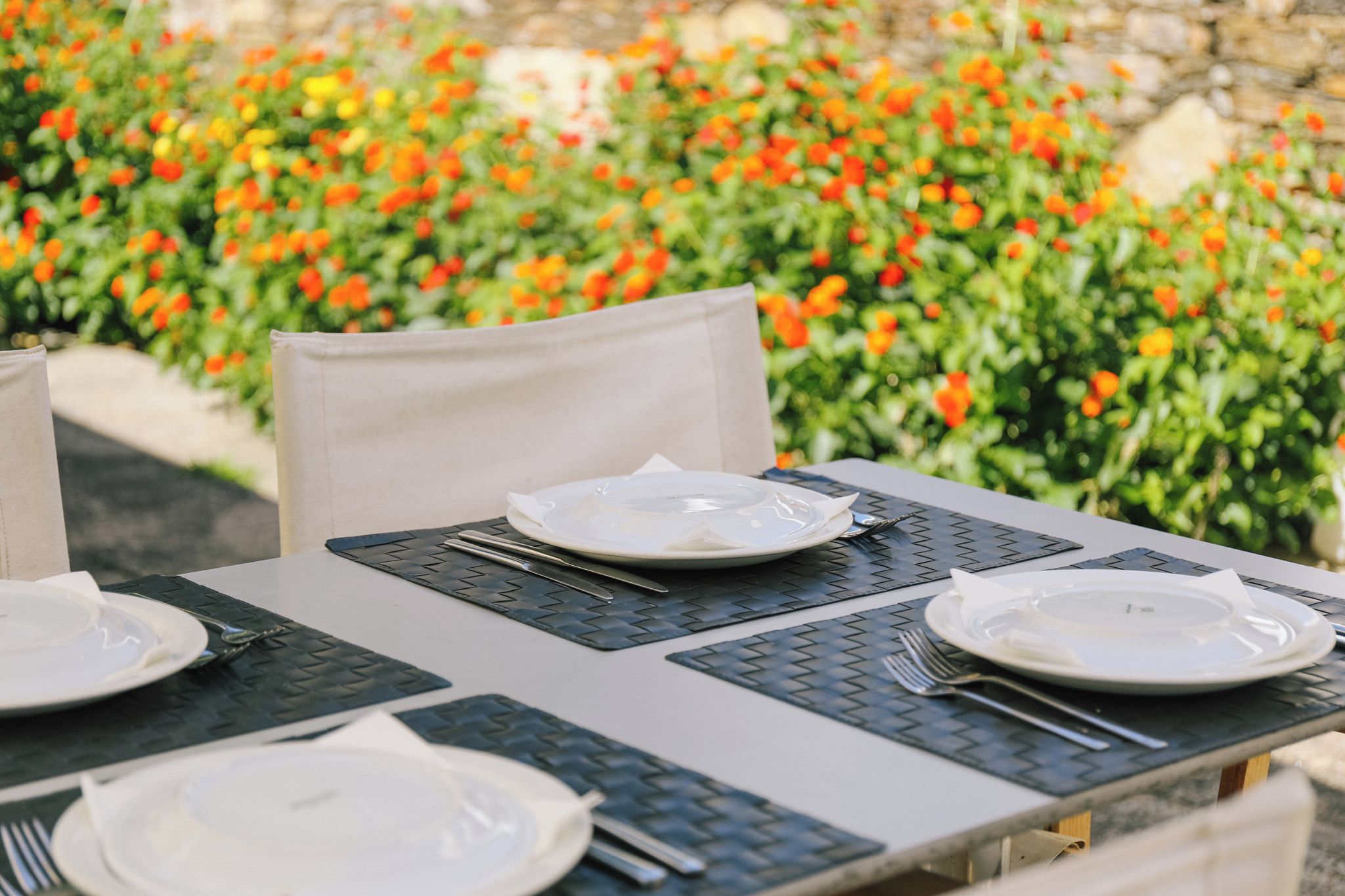 Une table dressée à l’extérieur, avec des assiettes, des couverts et des serviettes.