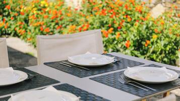 Una mesa al aire libre con platos, cubiertos y servilletas.