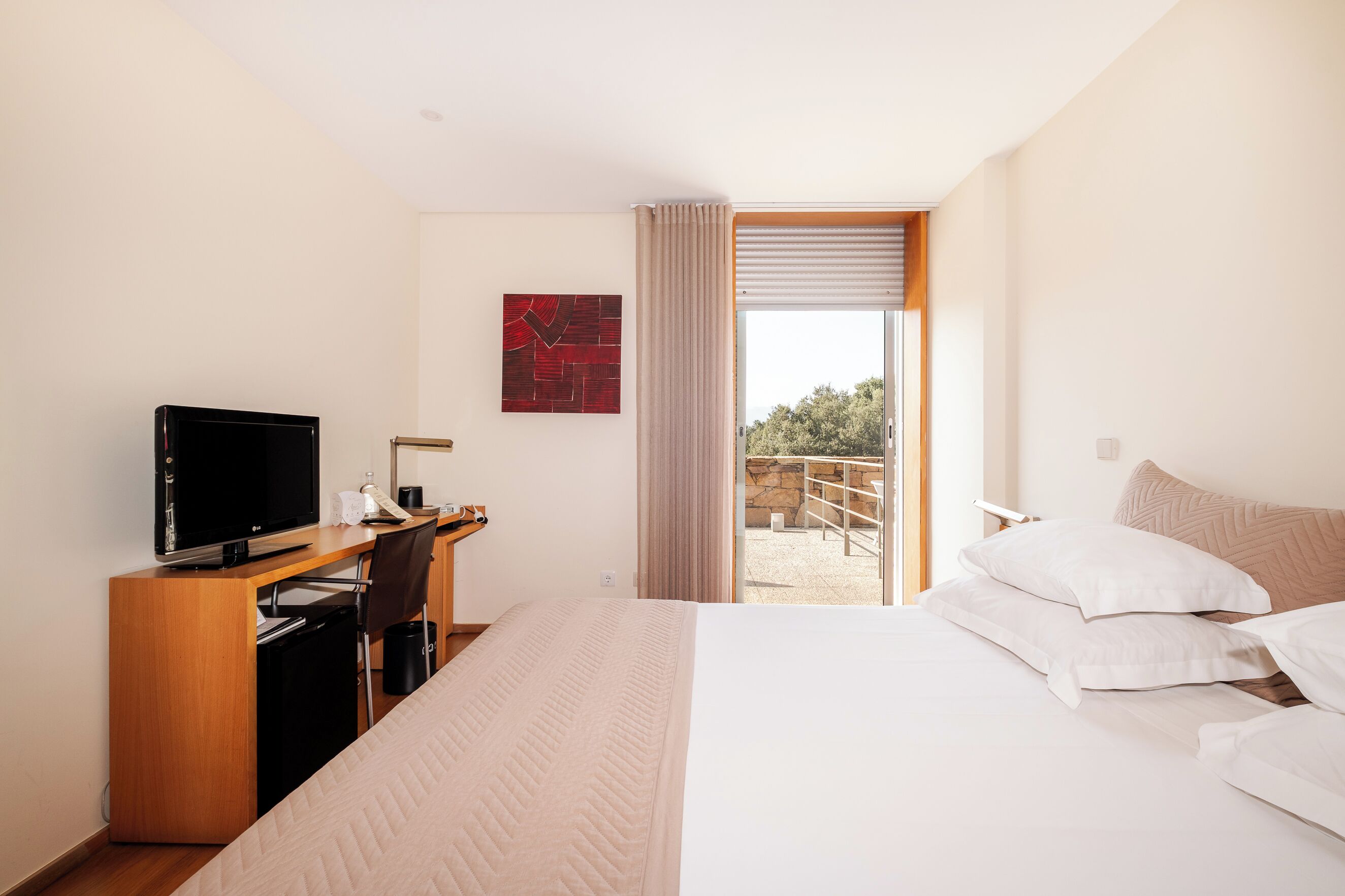 Une chambre d’hôtel avec un lit, un bureau équipé d’un ordinateur, une télévision et une vue sur l’extérieur.
