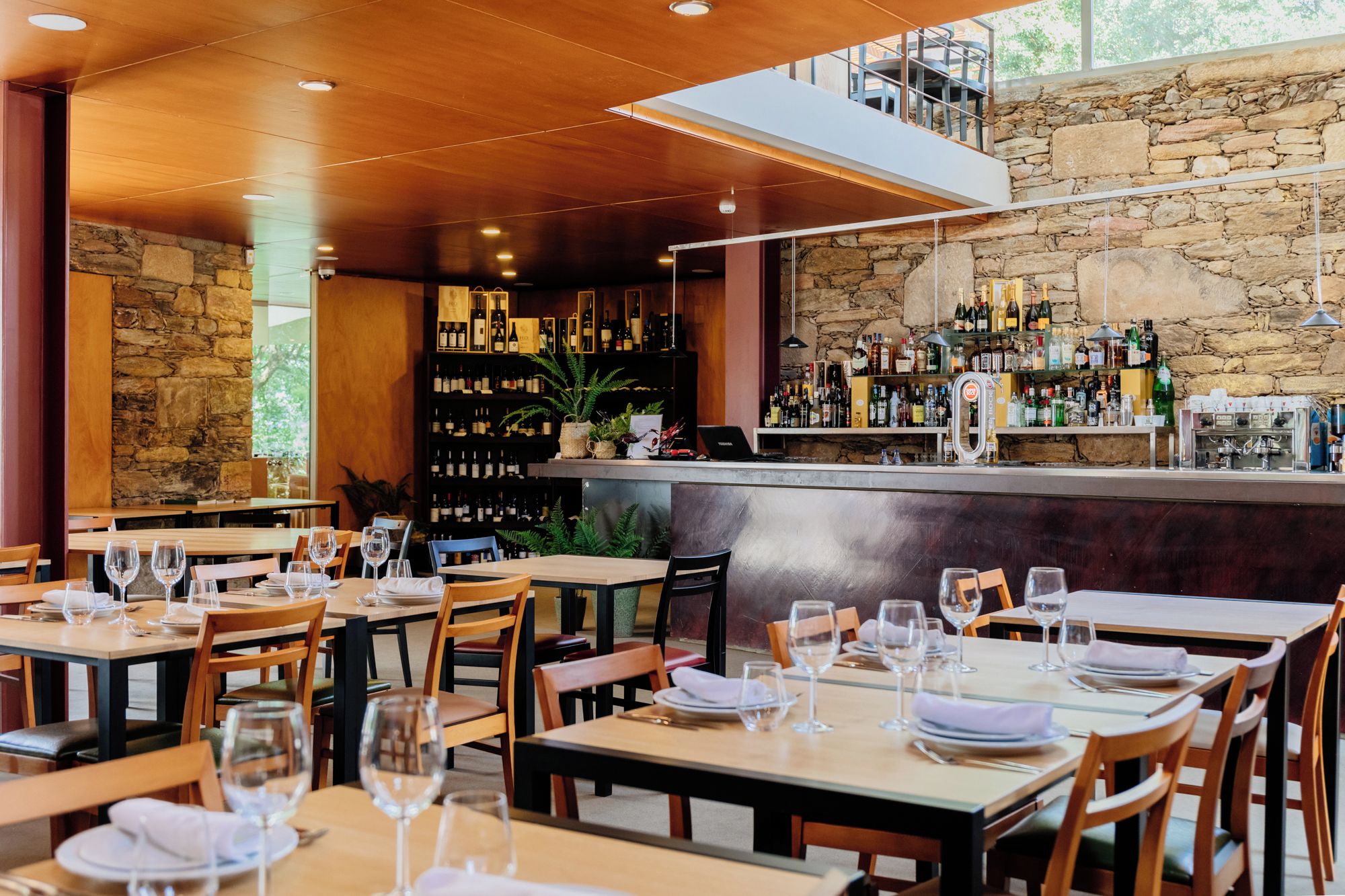 A restaurant with multiple tables, chairs, and a bar area with shelves of bottles.