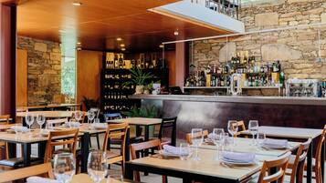 A restaurant with multiple tables, chairs, and a bar area with shelves of bottles.