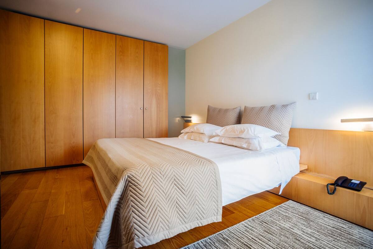 Een slaapkamer met een bed, een houten garderobe, bedlampen en een telefoon.