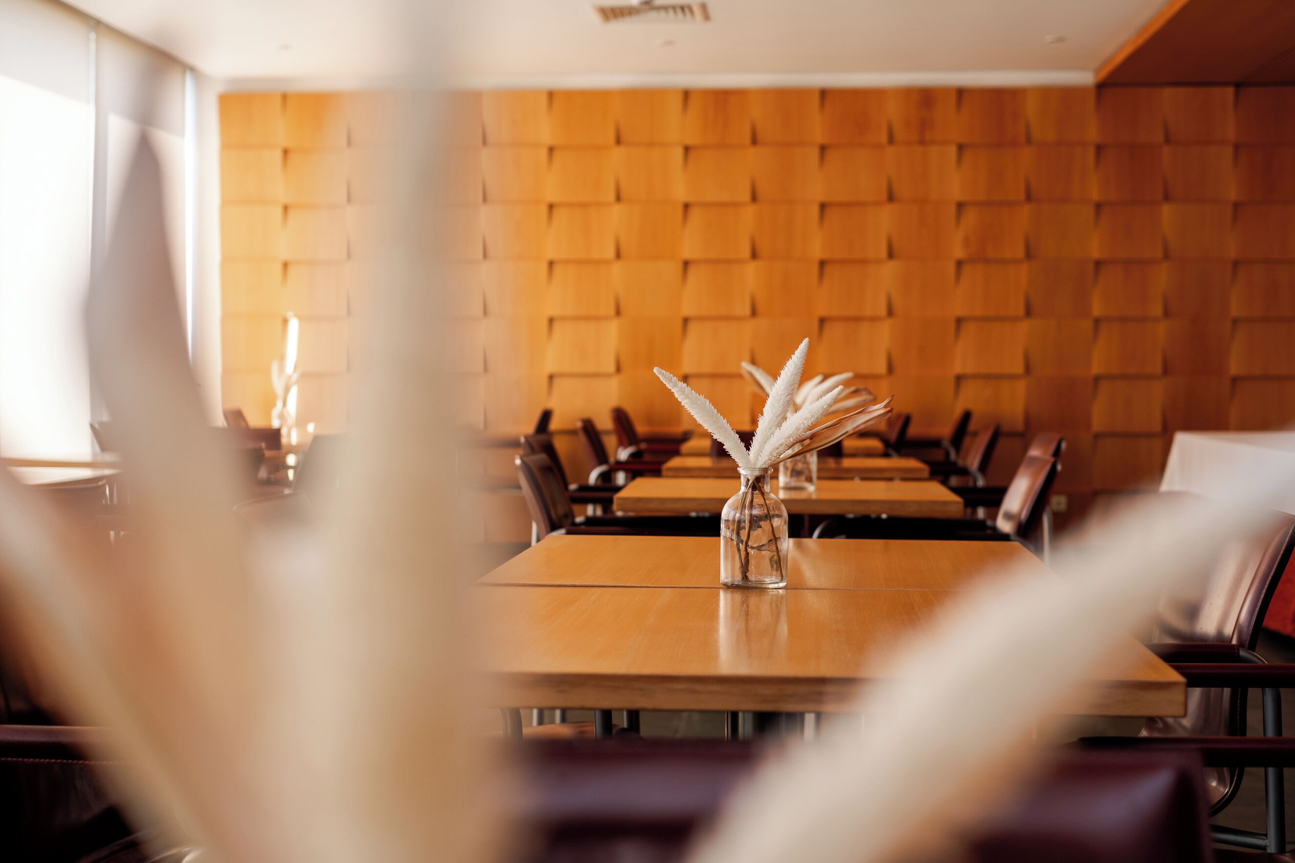 Een restaurant met houten paneelwanden, een centrale tafel met een bloemenvaas en lederen stoelen.