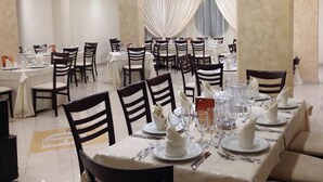 A banquet hall with multiple round tables, each set with white tablecloths, chairs, and silverware. - Cliffs Hotel (Joppolo)