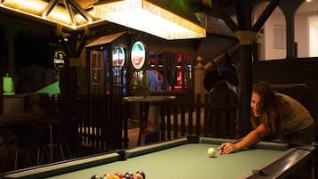 Una mesa de billar con bolas, un área de bar con un letrero de Guinness y un letrero de Red Bull.