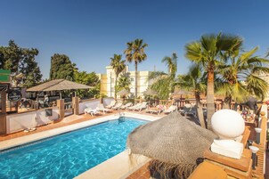 Una piscina al aire libre, sombrillas, sillones reclinables de piscina