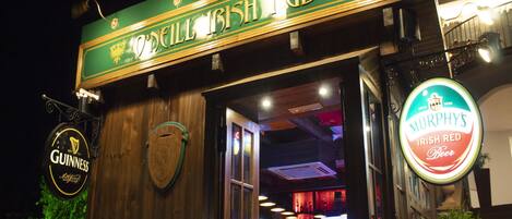 Un pub avec une enseigne verte, une affiche Guinness et une affiche Murphy's.