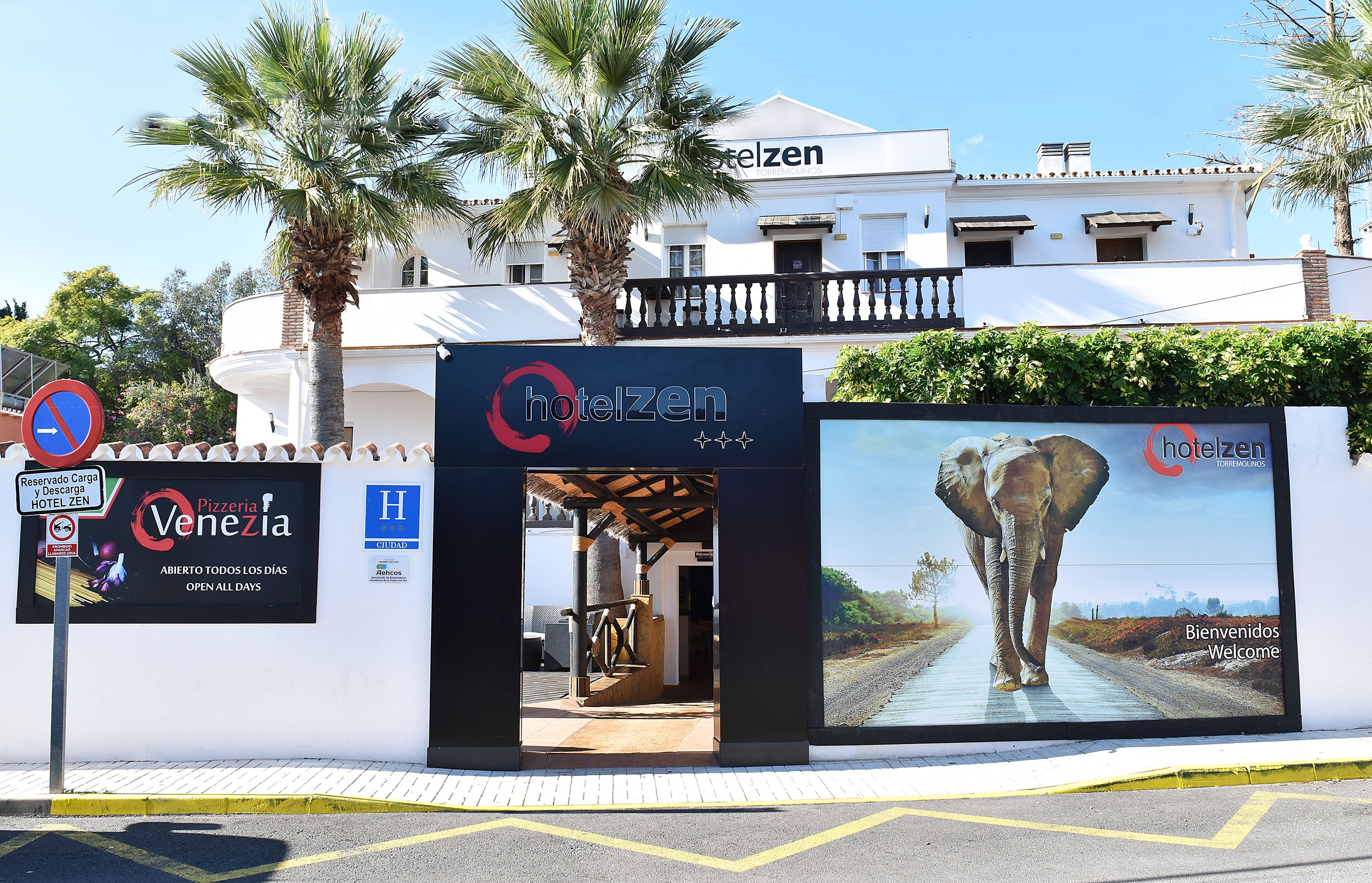 A hotel entrance with a sign for 'Hotel Zen' and a large billboard featuring an elephant.