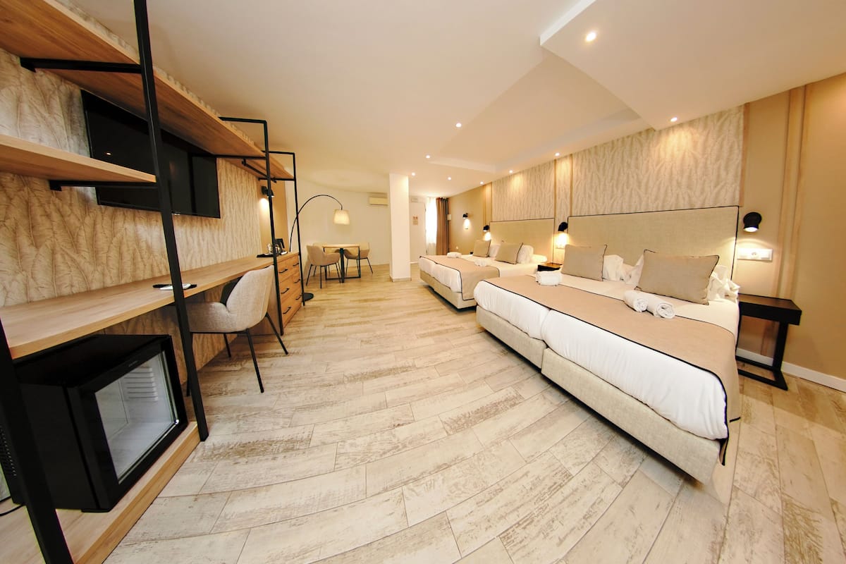 A modern hotel room with a long bed, a desk, and a TV.