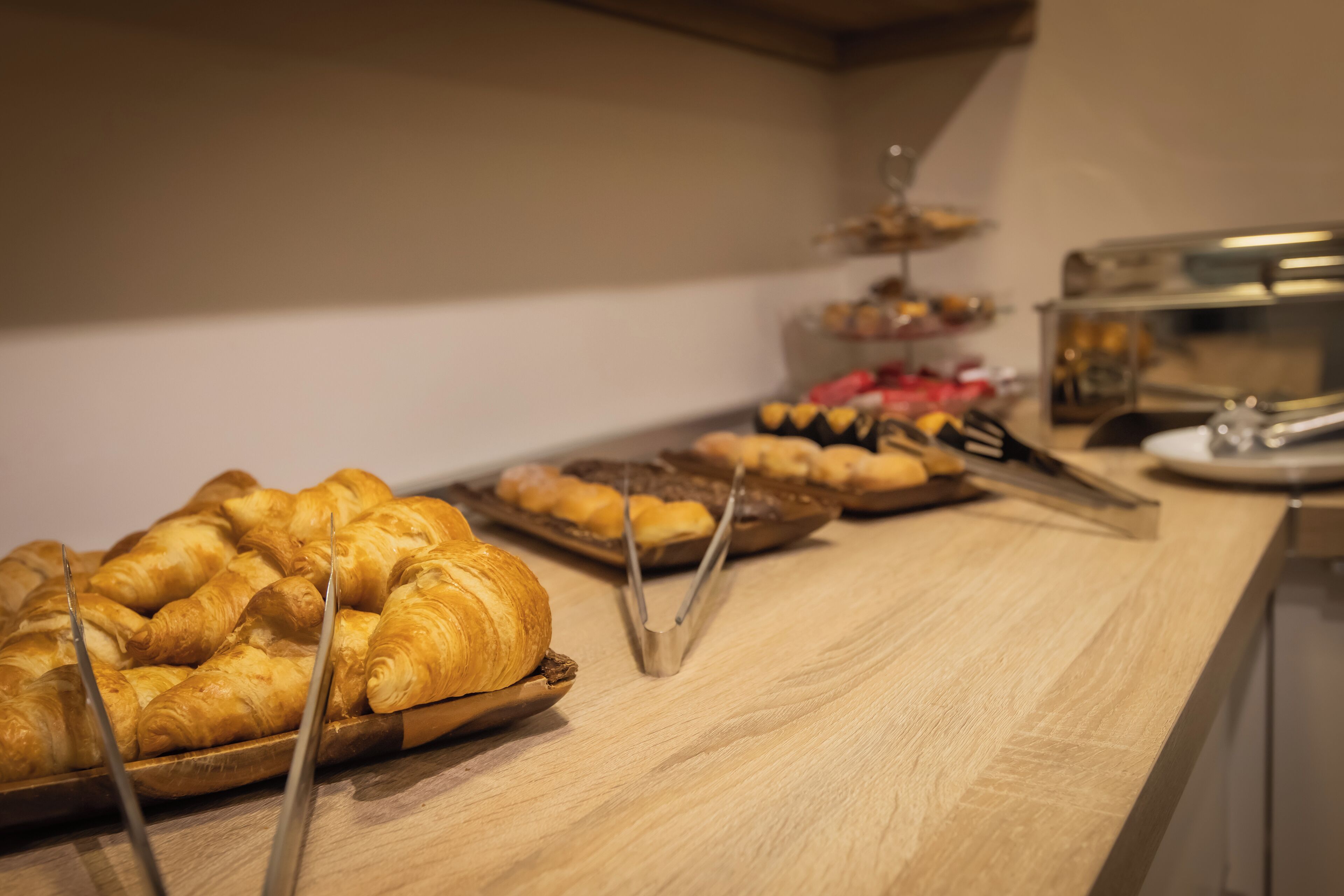 A buffet table with various baked goods including croissants and pastries.