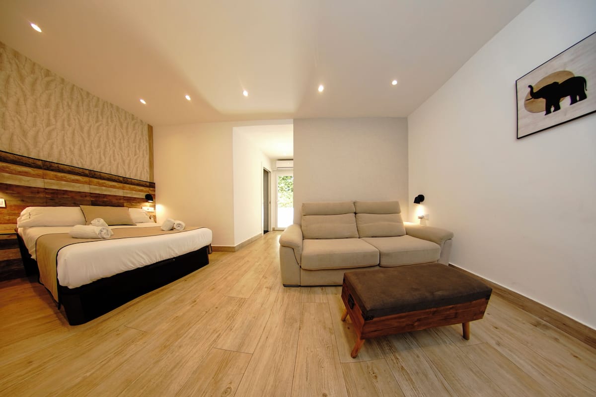 A bedroom with a bed, a sofa, and an ottoman.