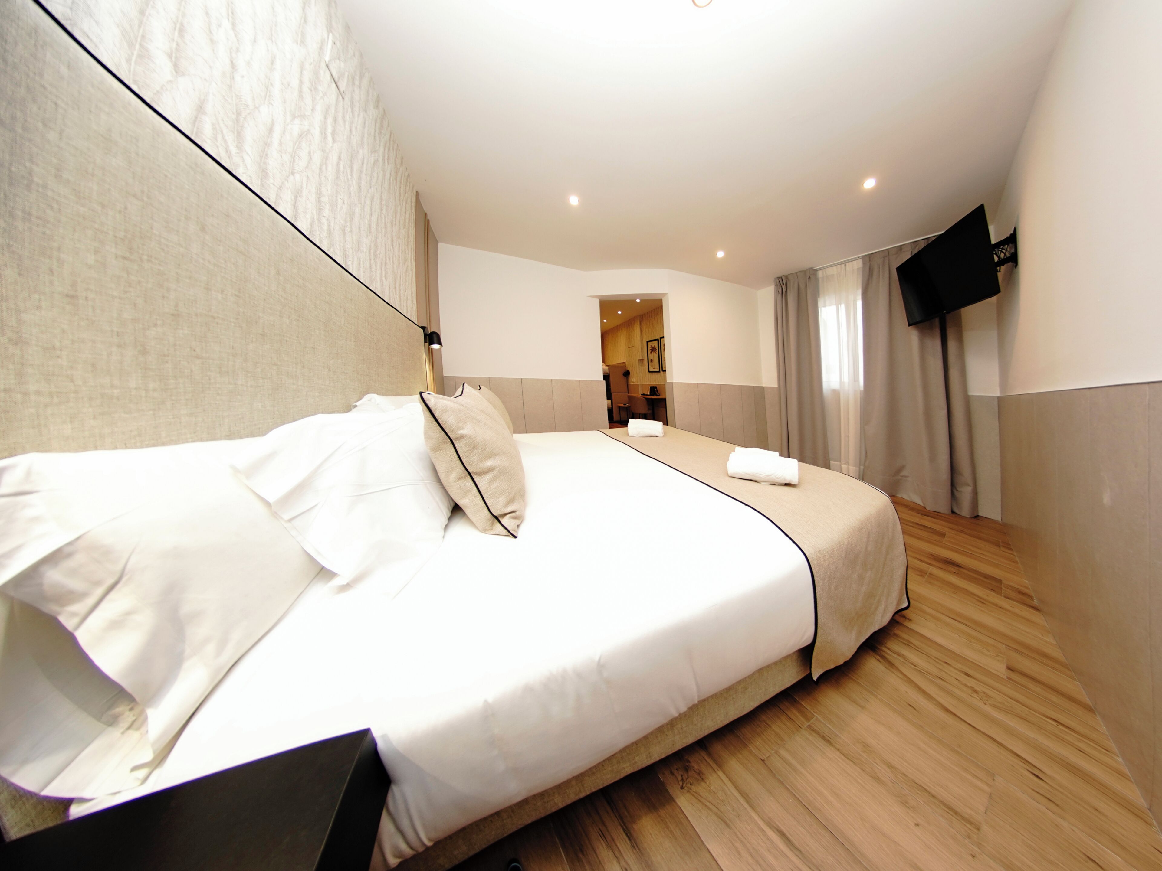 Ein Hotelzimmer mit einem großen Bett, einem Flachbildfernseher und Holzboden.