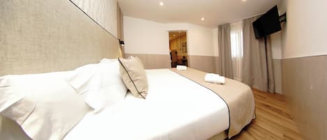Una habitación de hotel con una cama grande, un televisor de pantalla plana y piso de madera.