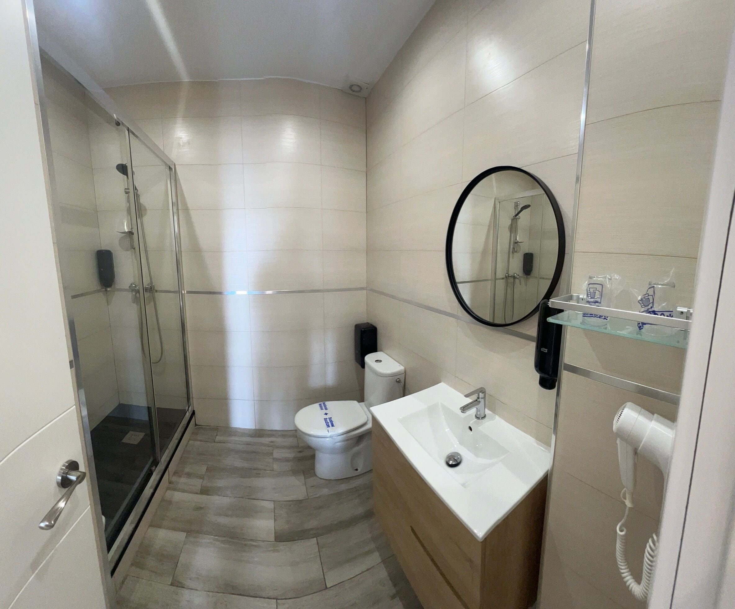 Een moderne badkamer met een douchecabine van glas, een toilet, een wastafel en een spiegel.
