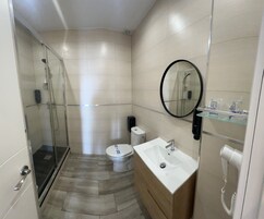 Een moderne badkamer met een douchecabine van glas, een toilet, een wastafel en een spiegel.