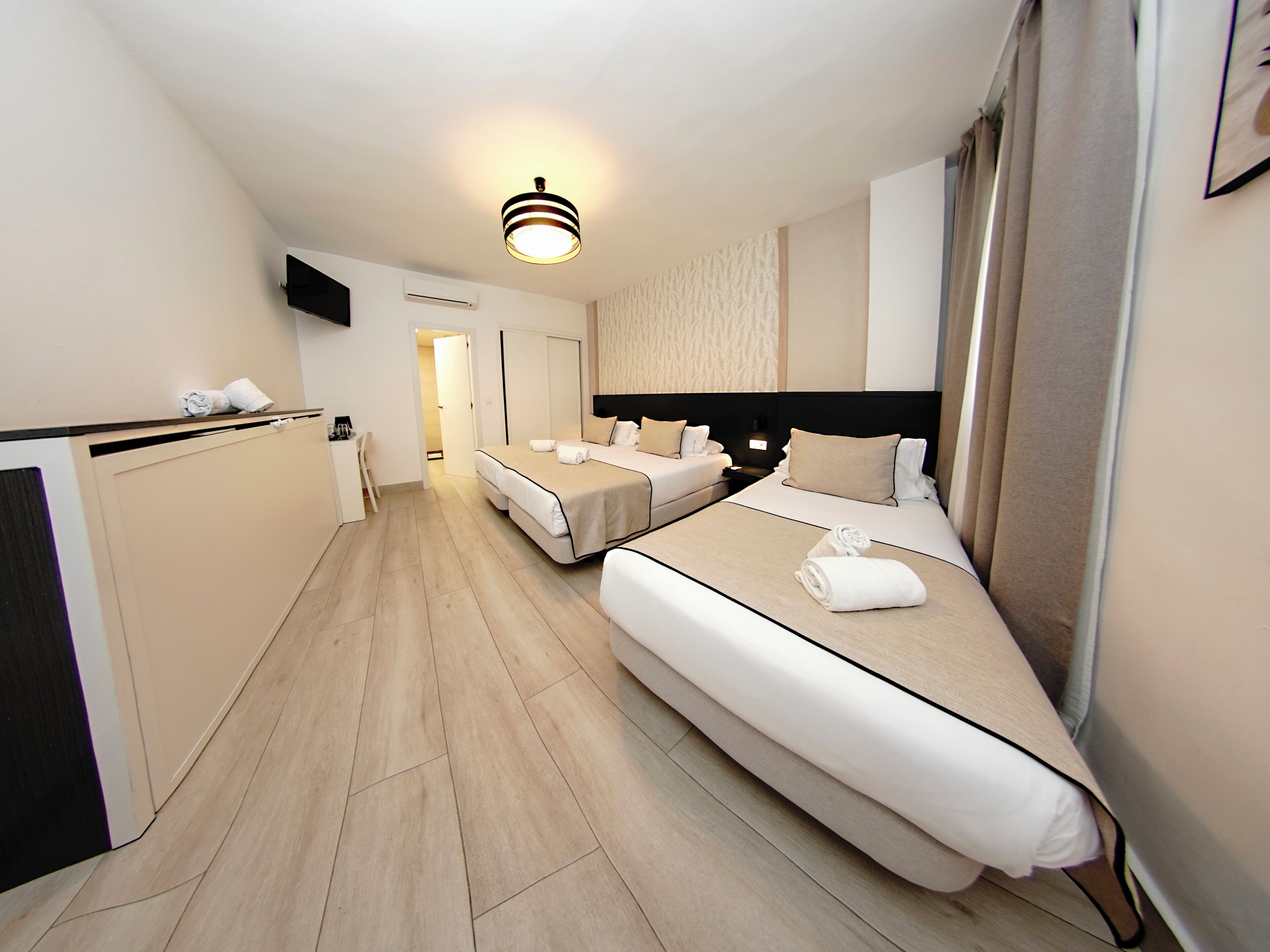 Habitación de hotel con dos camas, un escritorio y un televisor.
