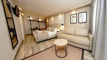 Een moderne hotelkamer met een bed, een bank, een klein rond tafeltje en een spiegel.