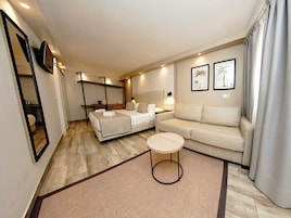 Une chambre d’hôtel moderne équipée d’un lit, d’un canapé, d’une petite table ronde et d’un miroir.