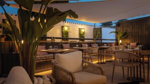 An outdoor seating area with wicker chairs and tables, surrounded by large plants and a wooden fence. - Hotel Zen Airport with Free shuttle (Torremolinos)
