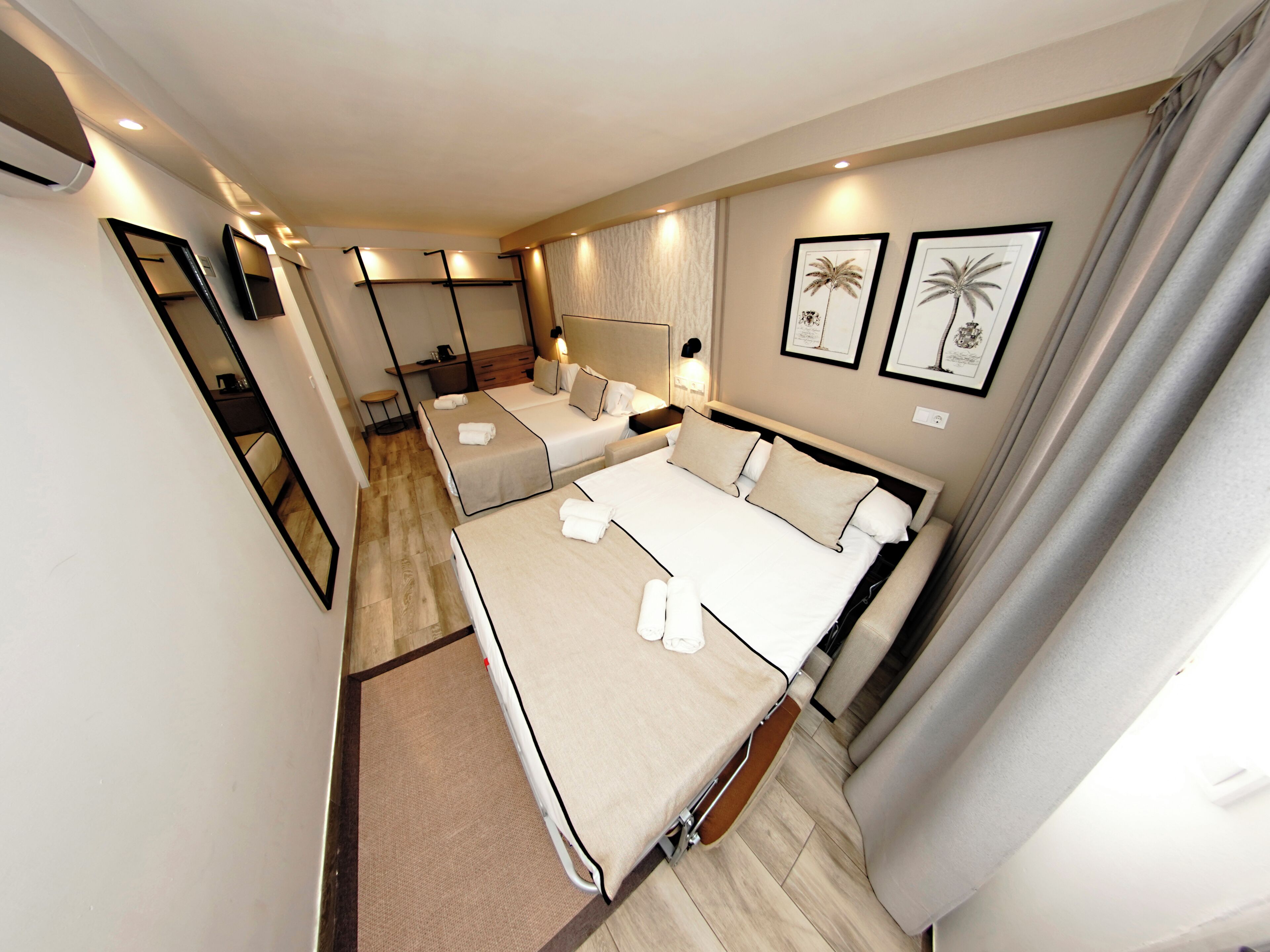 Een hotelkamer met een groot bed, een bureau, een stoel, een spiegel en twee ingelijste foto's aan de muur.
