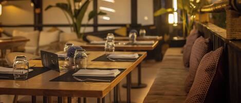 A restaurant with wooden tables and chairs, some with menus and glasses.