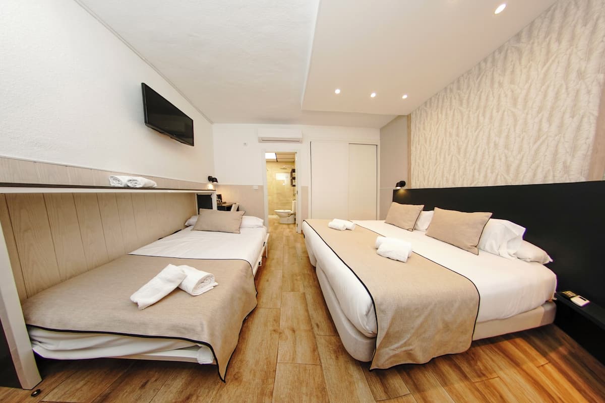 A hotel room with two beds, a TV, and a bathroom in the background.
