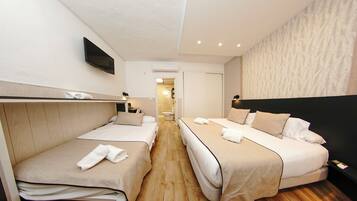 Habitación de hotel con dos camas, un televisor y un baño al fondo.