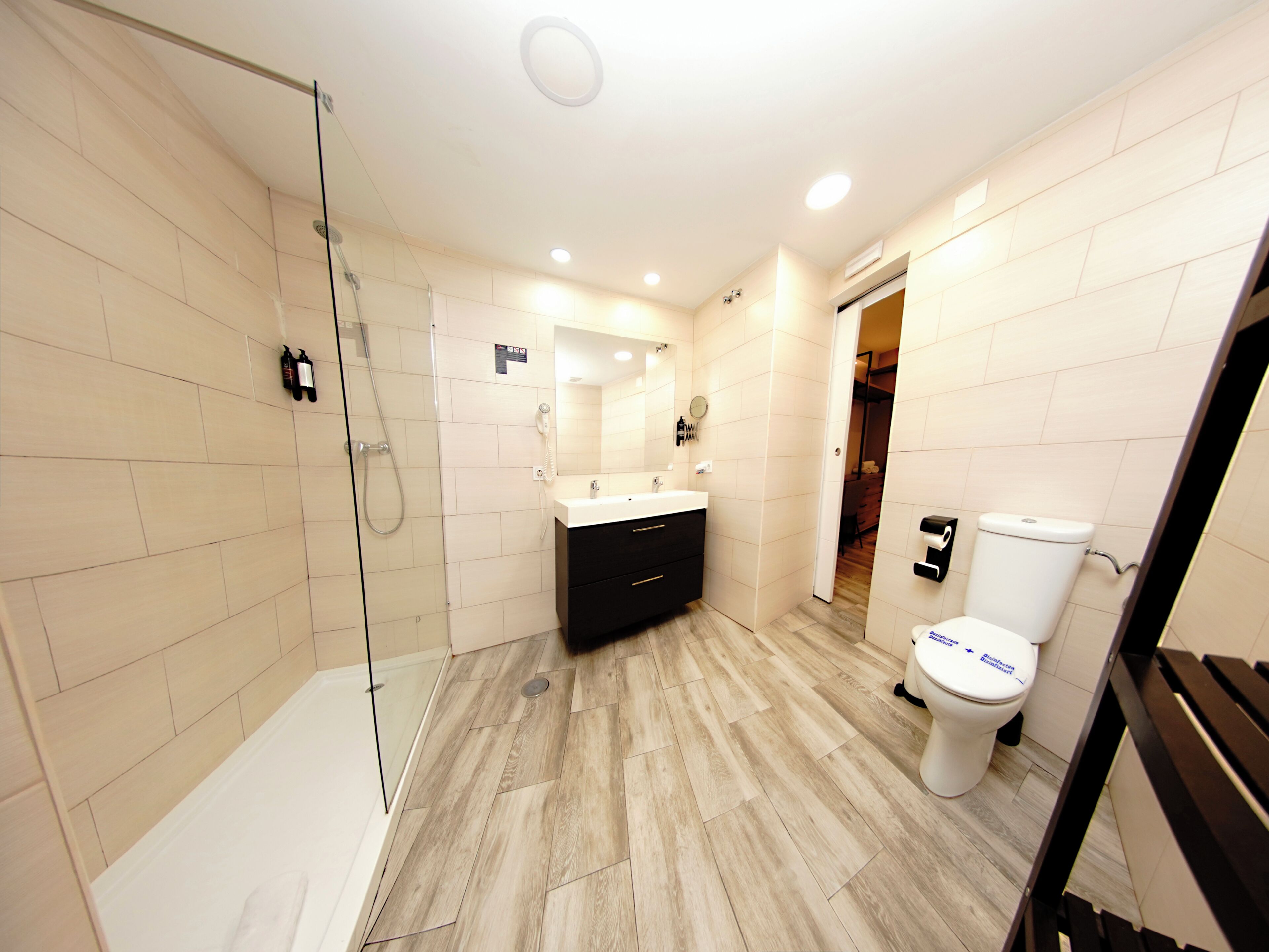 A modern bathroom with a glass shower enclosure, a white toilet, and a black vanity.