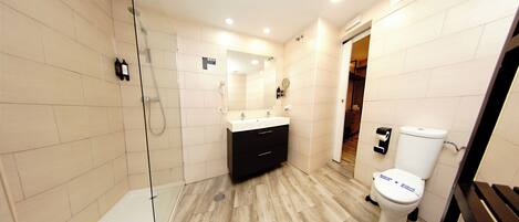 A modern bathroom with a glass shower enclosure, a white toilet, and a black vanity.