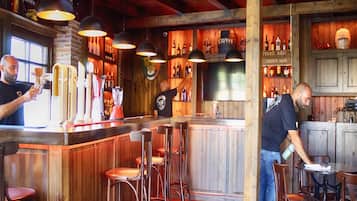 A bar with wooden interiors, bar stools, and a variety of bottles on shelves.