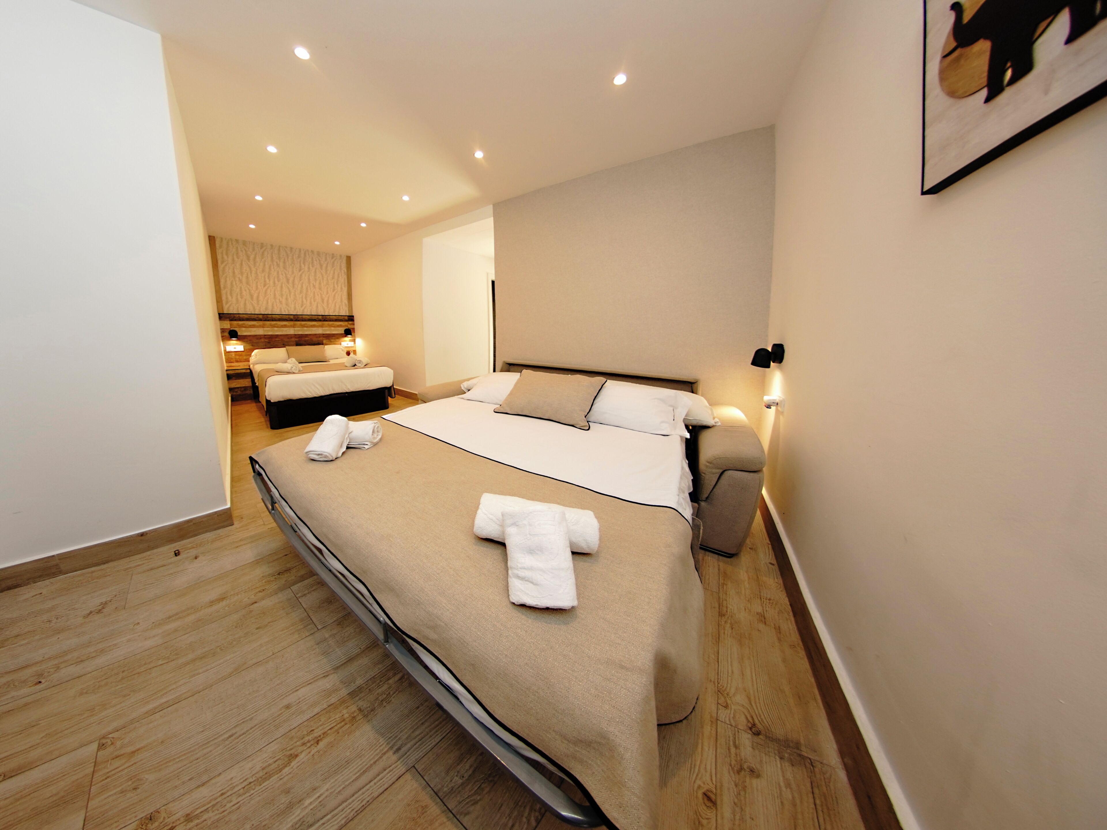 Een hotelkamer met een groot bed, nachtkastjes, een kunstwerk aan de muur en een houten vloer.