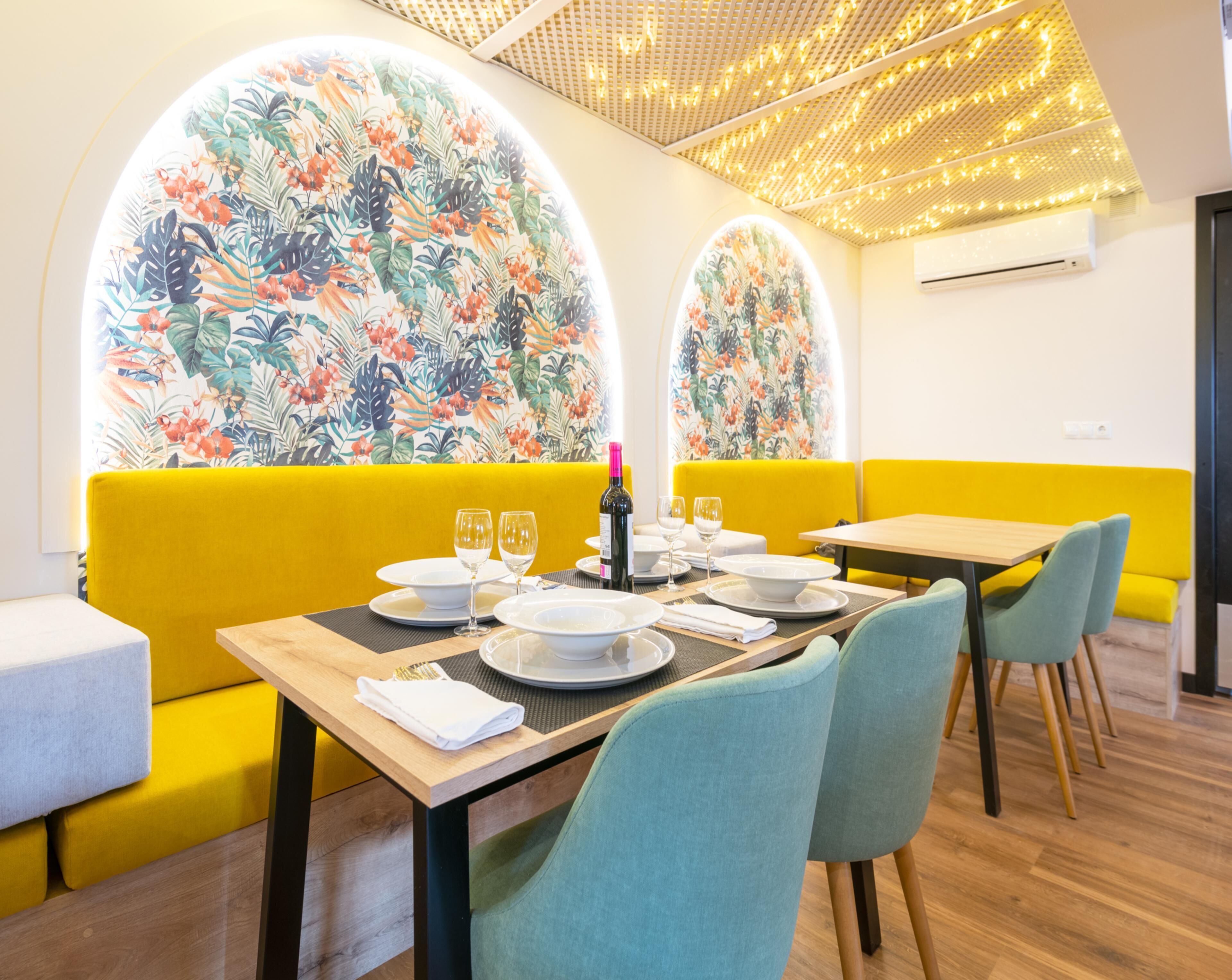 A dining area with yellow booths, a wooden table, and floral wall art.