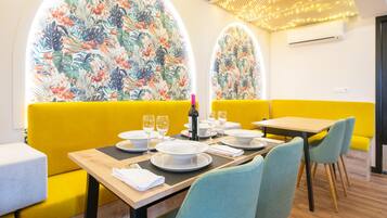 A dining area with yellow booths, a wooden table, and floral wall art.