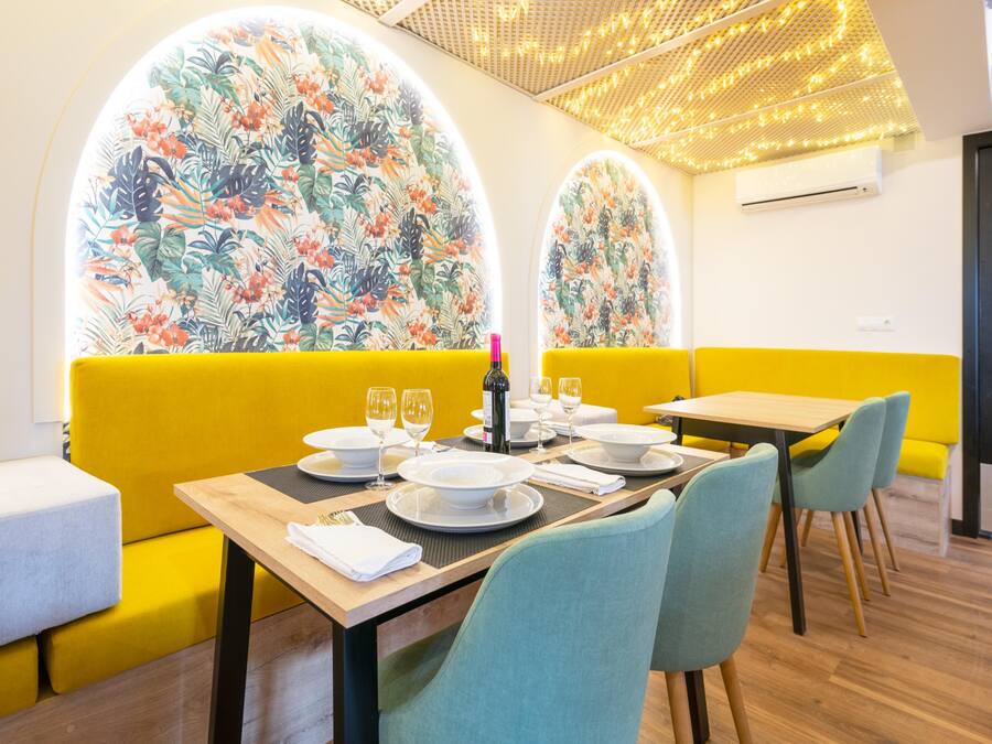 A dining area with yellow booths, a wooden table, and floral wall art.