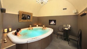 A spa room with a hot tub, a fireplace, and a chandelier. - Chateau St Havel (Prague)
