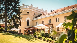 A building with a curved facade, outdoor seating area, and a well-maintained garden. - Chateau St Havel (Prague)