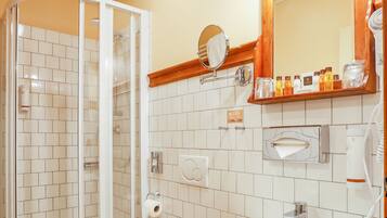 A bathroom with a glass-enclosed shower, a toilet, a sink, and a mirror above the sink.