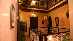 A corridor with ornate metal railings, a wooden ceiling, and a door with a decorative archway. - Riad du Petit Prince (Marrakech)