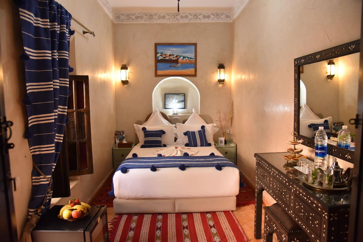 Une chambre à coucher comprenant un lit, une table de chevet, une commode, un miroir et un téléviseur fixé au mur.