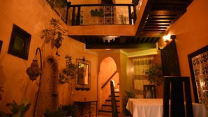 A cozy interior with a staircase, a dining area, and a balcony with plants. - Riad du Petit Prince (Marrakech)